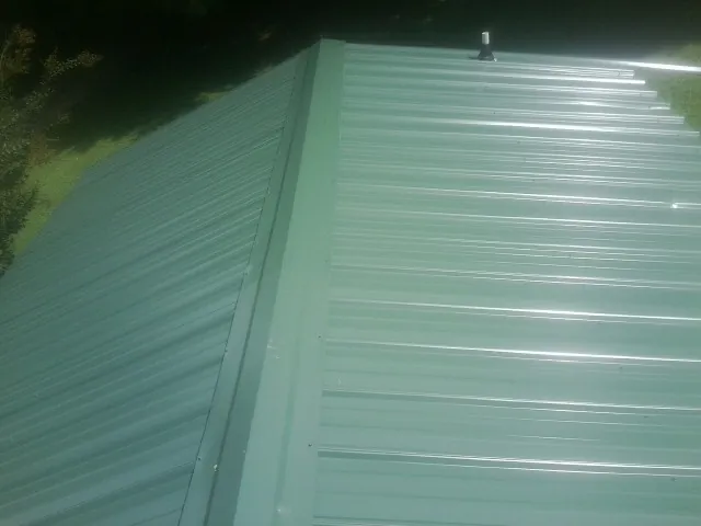 New green metal panels meeting at the ridge of a roof — Flat Roof Repair work by our crew in Lester