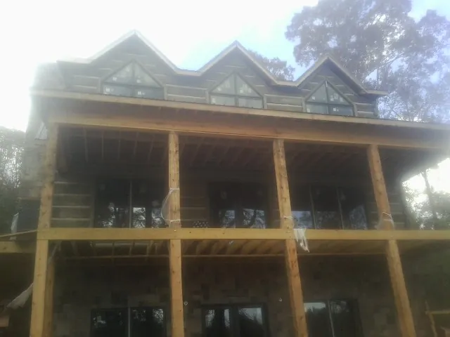 Dormers and porch framing on a large log home under construction — Roof Coating work by our crew in Lester