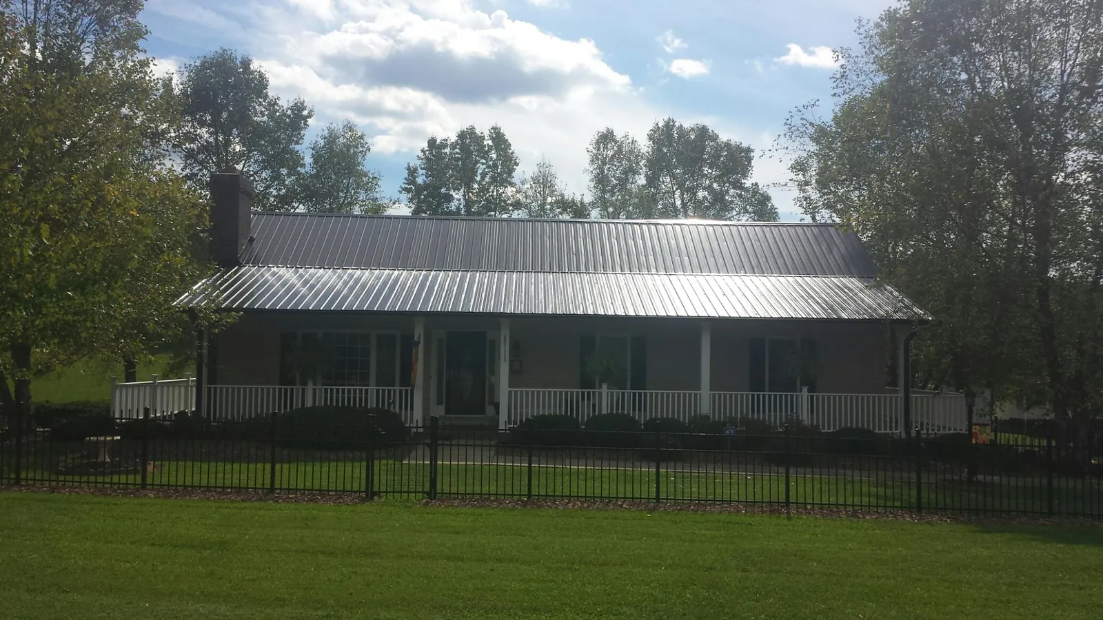 Gray metal roof on a brick ranch with a full width front porch — Gutter Guard Installation work by our crew in Lester