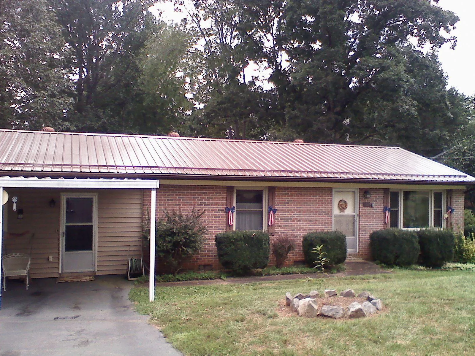 Bronze metal roof and carport on a brick ranch home — Roof Repair work by our crew in Lester