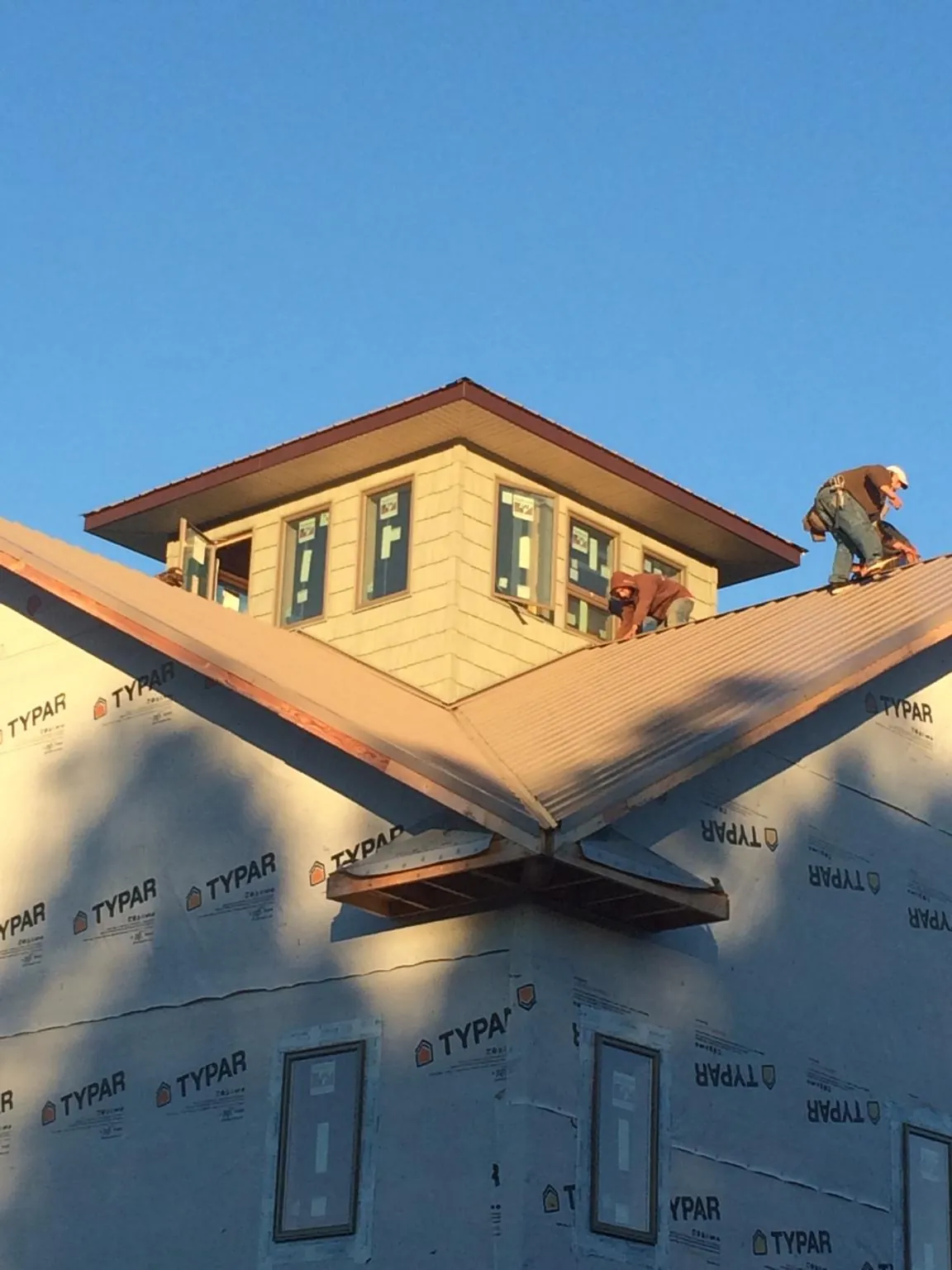 Roofers working around a rooftop cupola on a new metal roof at sunset — Roof Waterproofing in Lester by Roofing Brothers